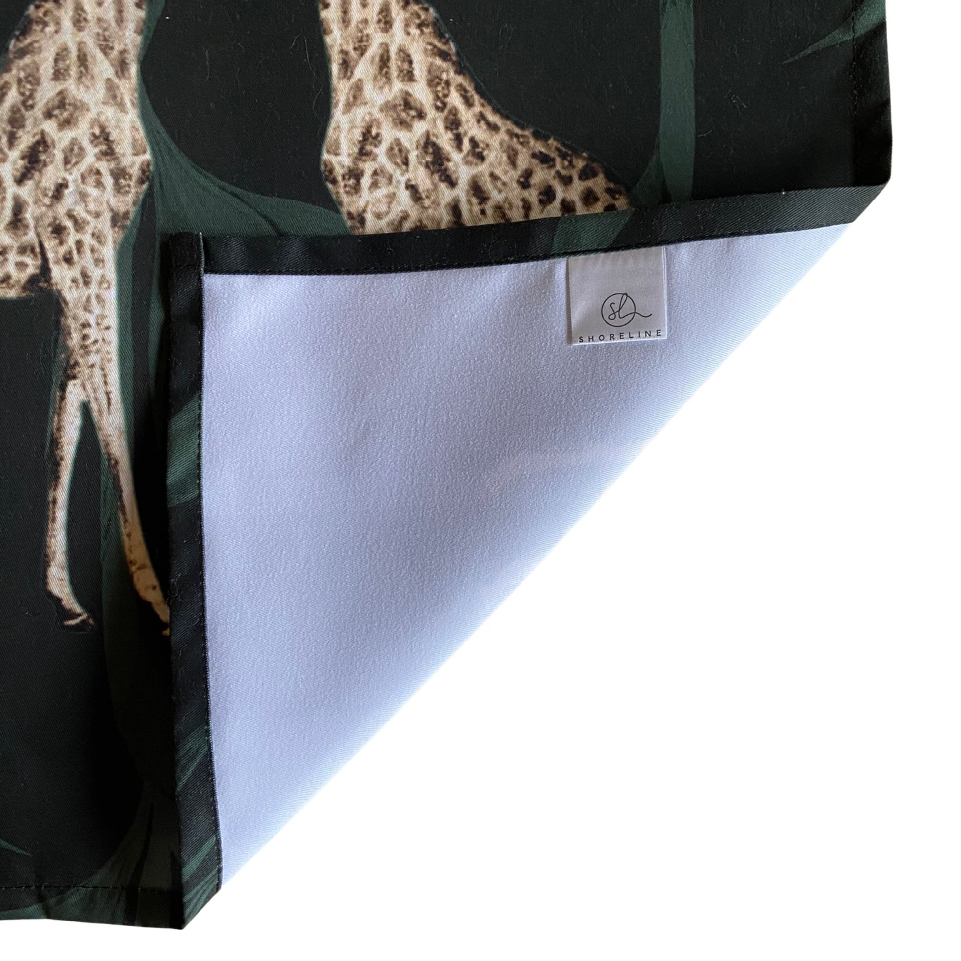 Folded fabric with a leopard print design on a black background, featuring a brand label.