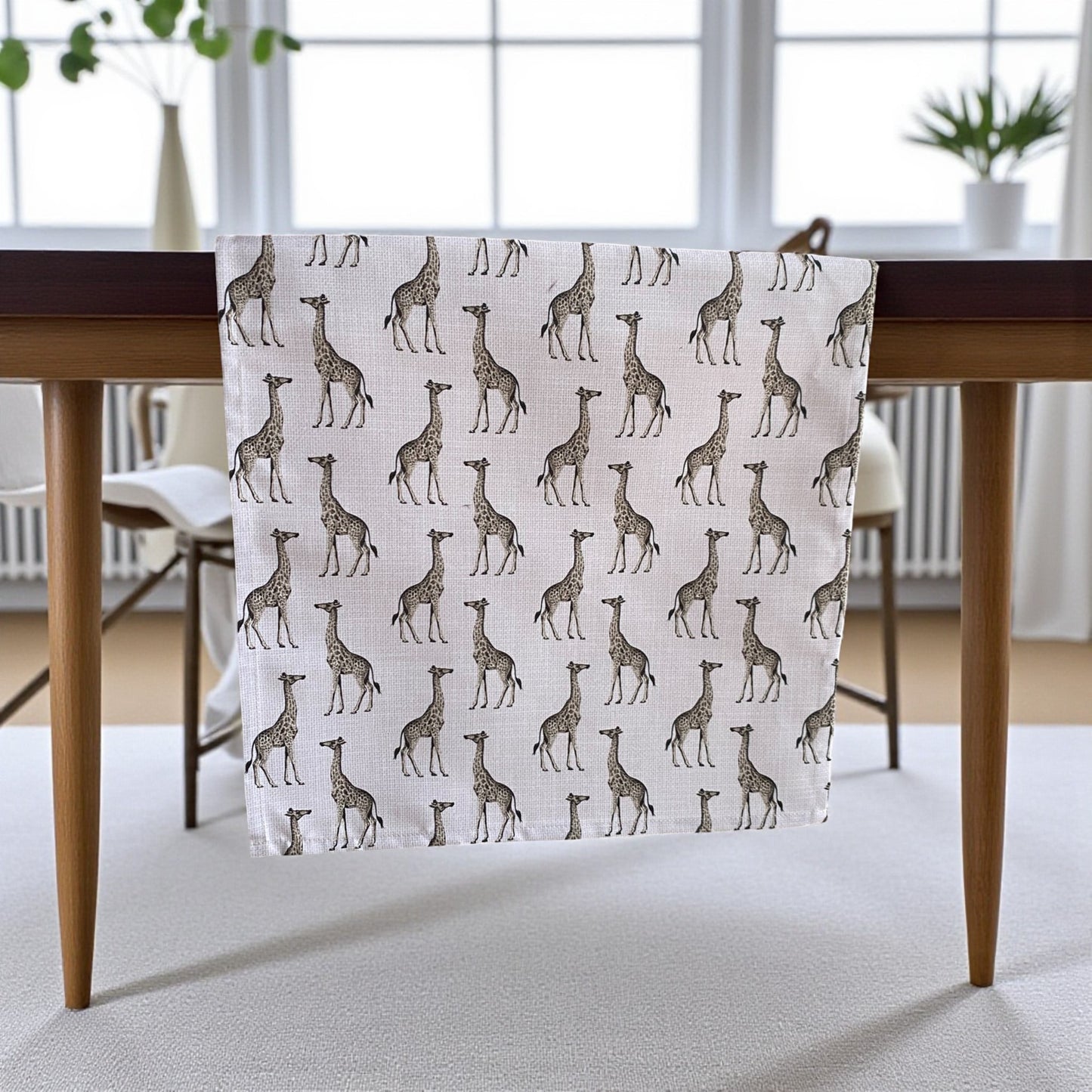 Table runner with giraffe pattern on a wooden table in a room with large windows.