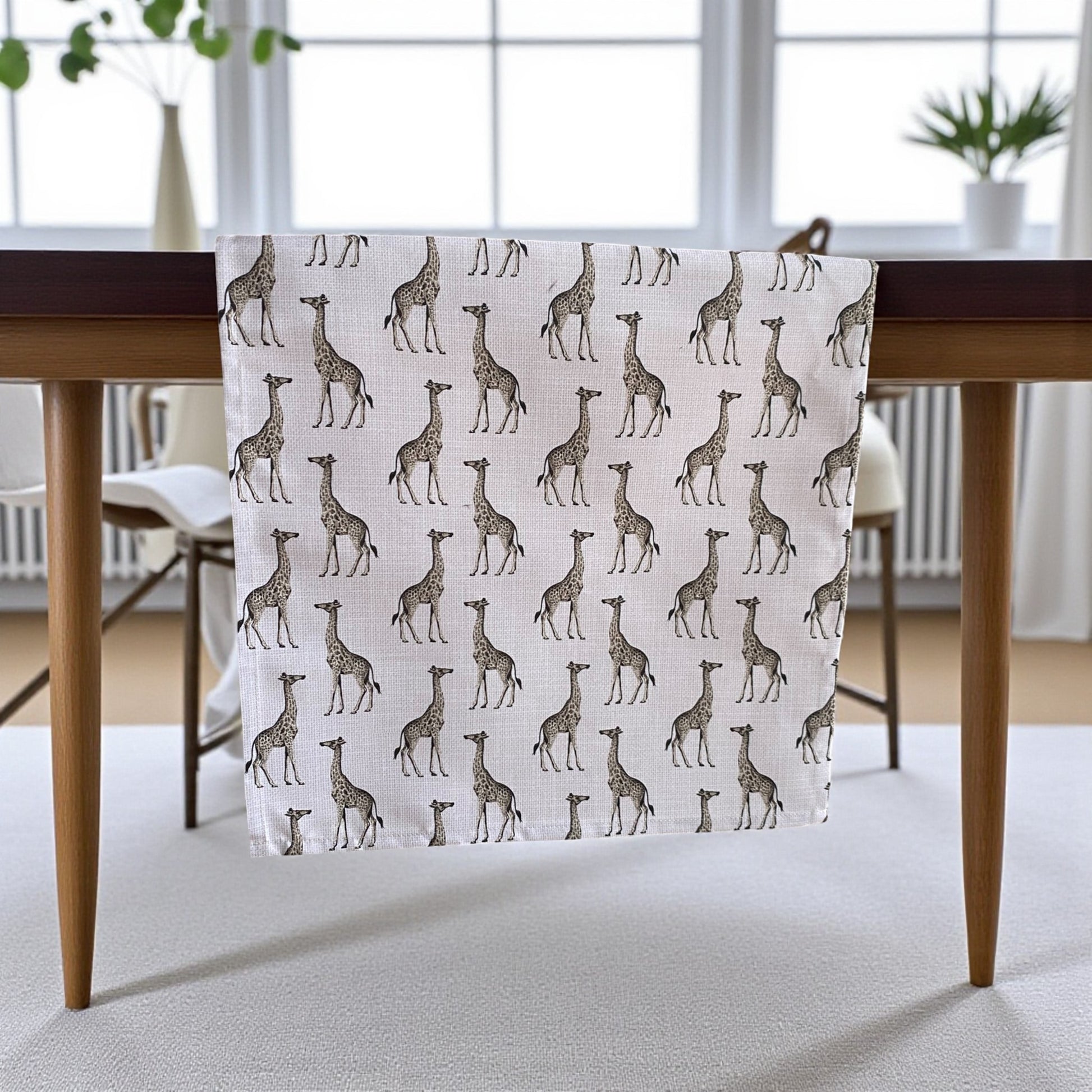 Table runner with giraffe pattern on a wooden table in a room with large windows.
