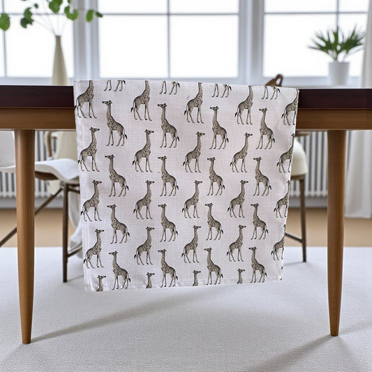 Table runner with giraffe pattern on a wooden table in a room with large windows.
