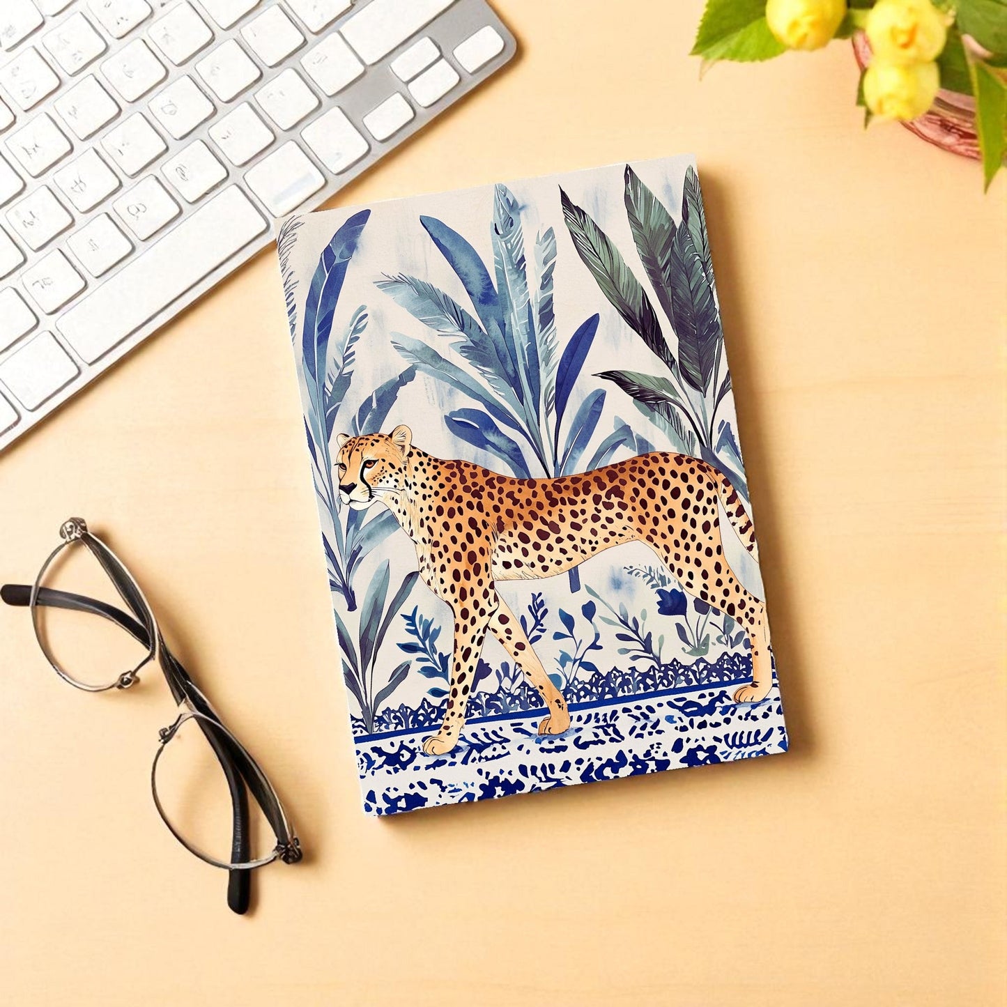 Notebook with a leopard design on a desk with glasses and a keyboard