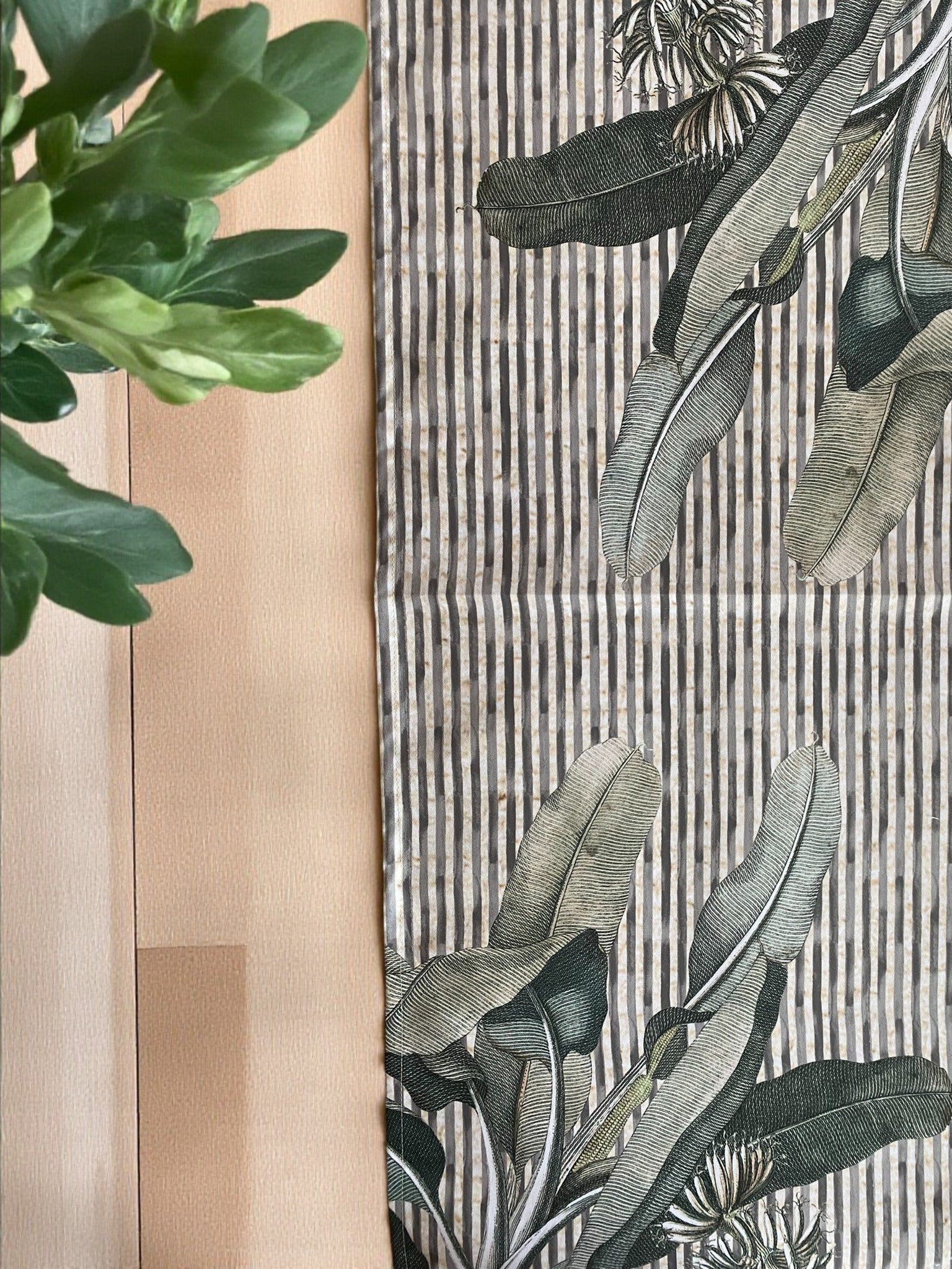 Close-up of a table runner with a floral pattern and a wooden surface.